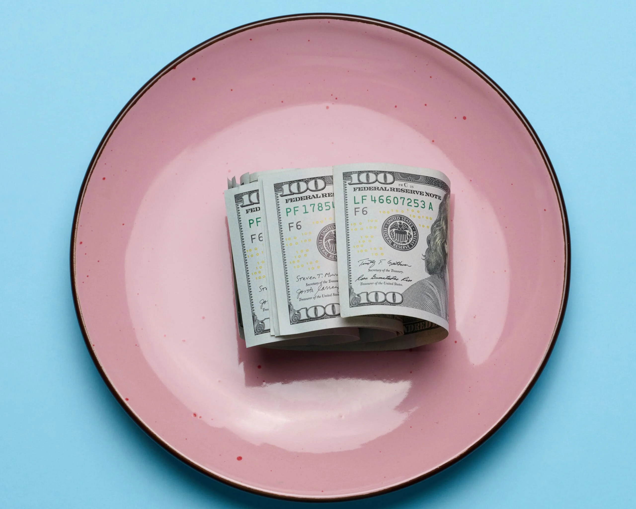Dollar bills in a ceramic pink plate scaled.jpg
