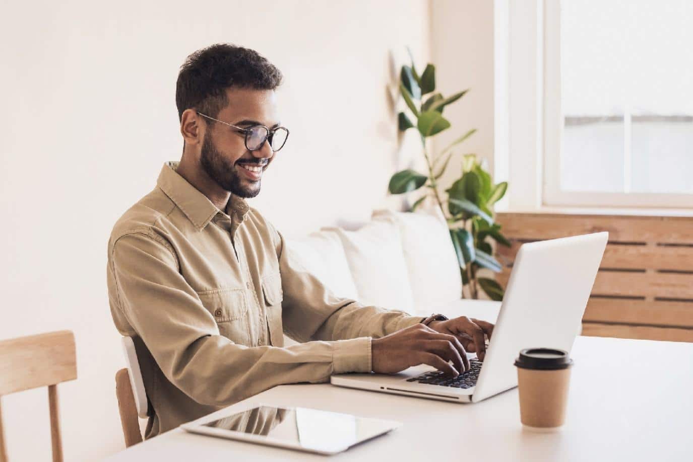 How to plan a workation as a freelancer freelancer smiling while working on a laptop at a bright tab.jpeg